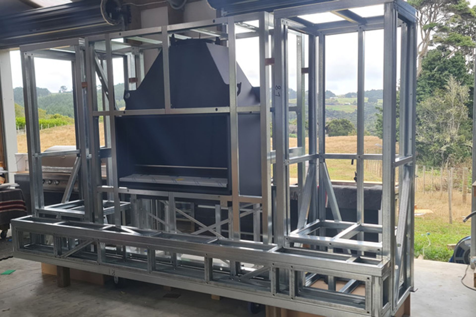 The fireplace was installed using the Escea EK Kitset Framing System with boxes for wood added either side. It was then surrounded by fibreboard, fixed into a steel frame, and finished with a render.