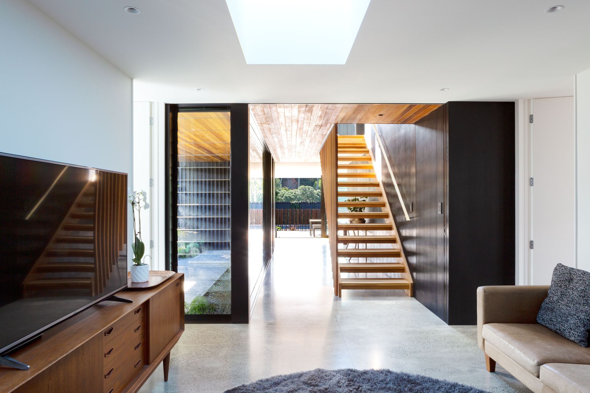 The view from the teenagers’ lounge through the entry foyer and out through the backyard. The change in ceiling material adds to the feeling of separation in the open space, says Tim.