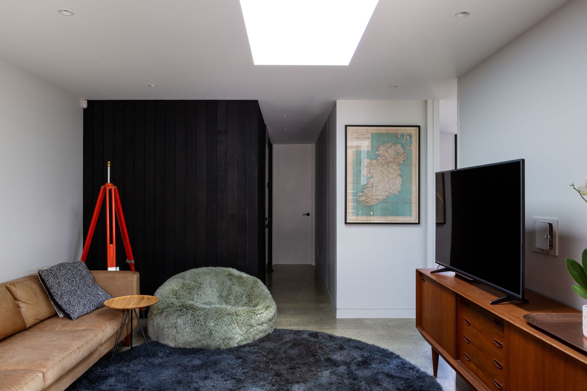 The teenagers’ lounge is painted Resene Black White. “My father in law was a cattle dealer in Ireland. So that's an old old roadmap, a fabric one, that we had mounted and framed,” says homeowner Rina Crawford of the artwork.