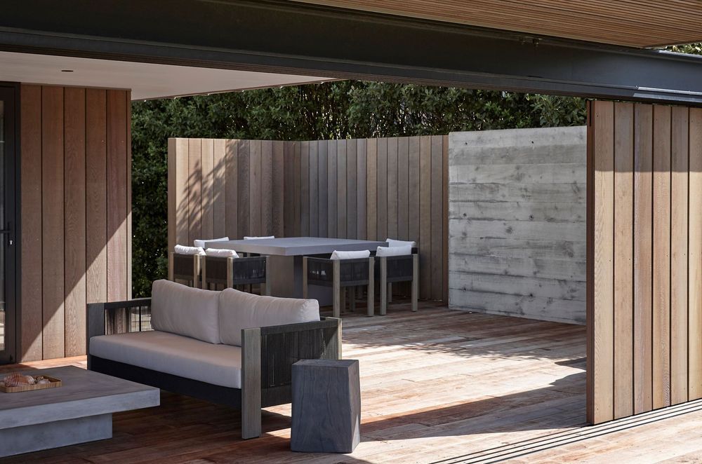 To the rear of the house, a second covered outdoor living space provides ample room for the extended family to spread out. Cedar softens the floors and walls here, integrating it into the environment.