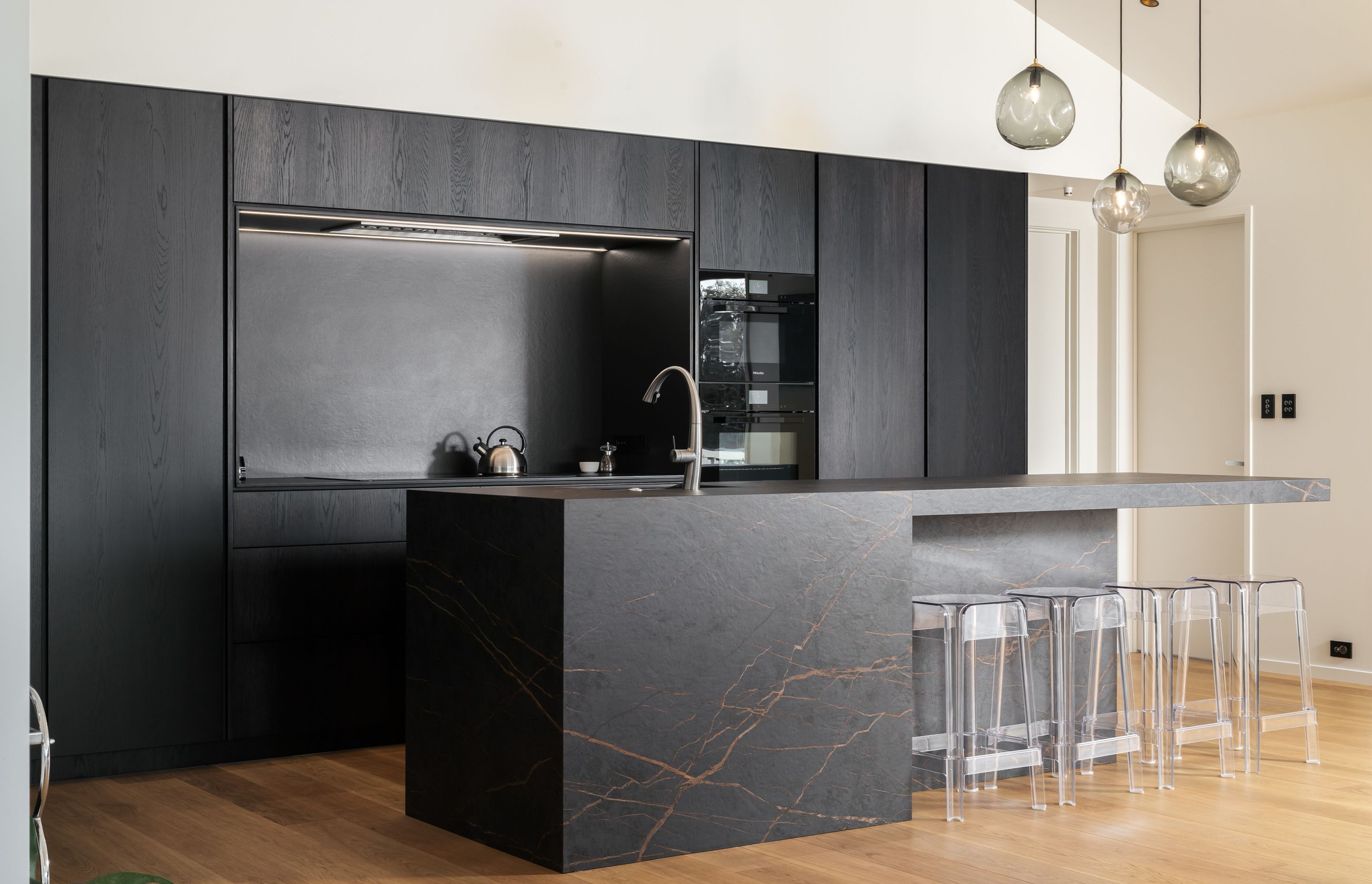 The kitchen features dark stone and black cabinetry – a contrast to the rest of the space.