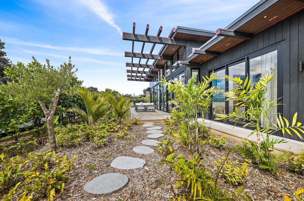 Designed by Hulena Architects, the Omaha home was constructed by Bridgens Construction and Design. It offers plenty of indoor-outdoor flow, ideal for the coastal environment. Stained in Resene Crowshead, the cedar is the perfect backdrop for the surrounding plants.