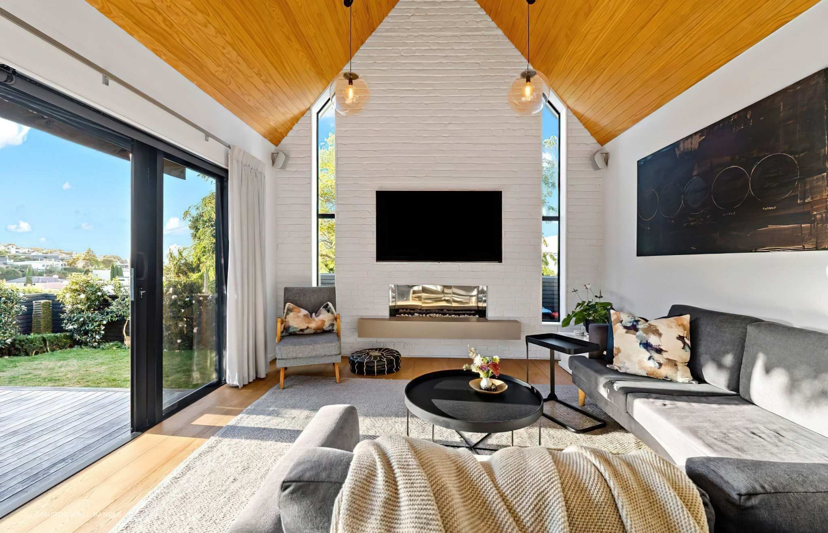 In this home, a feature wall was added to the living room in Muros White Loft Brick panels, painted in a custom Resene colour similar to Resene Half Rice Cake. Design by Blackbird Projects.