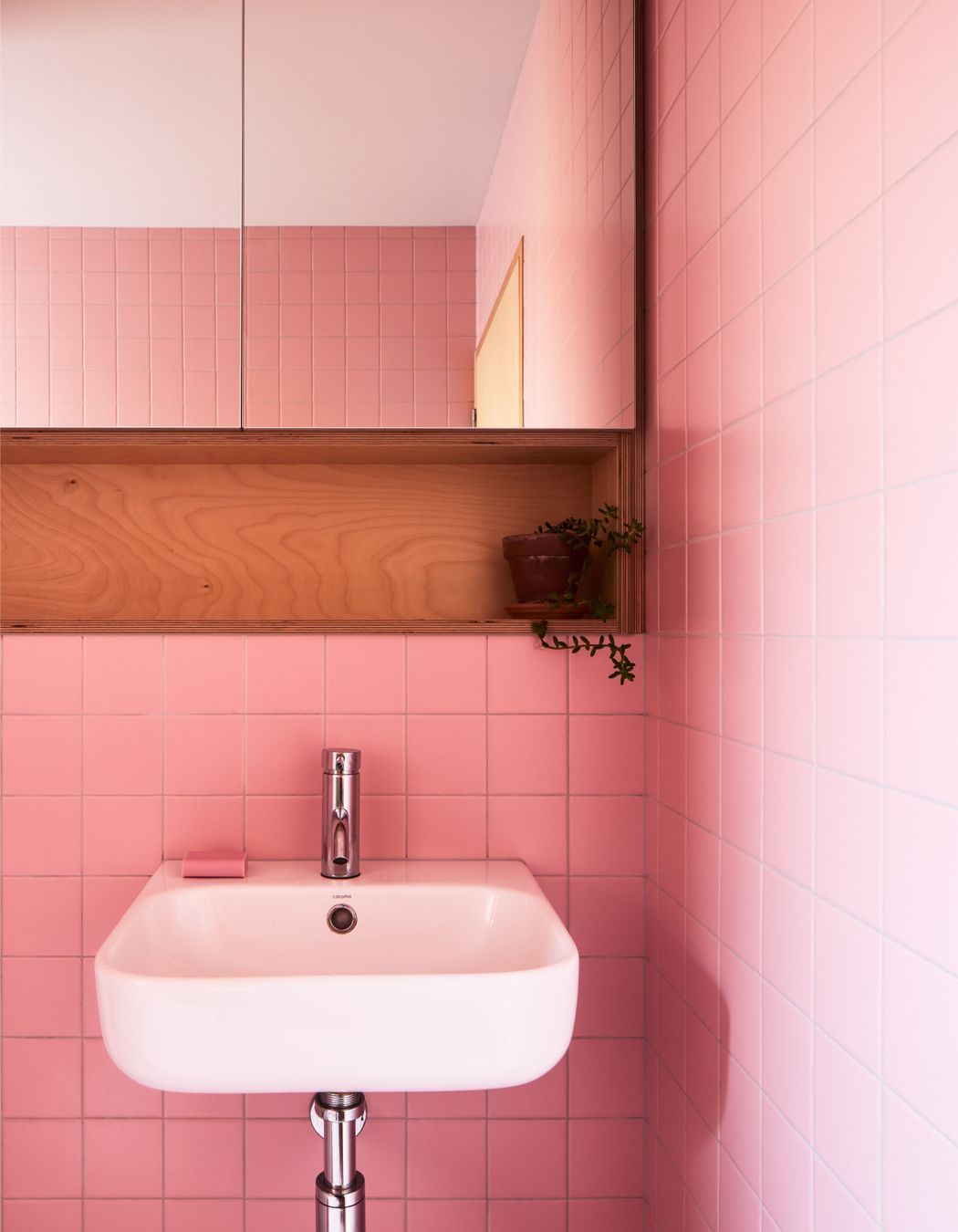 Pink bathroom tiles inject joy into everyday rituals.