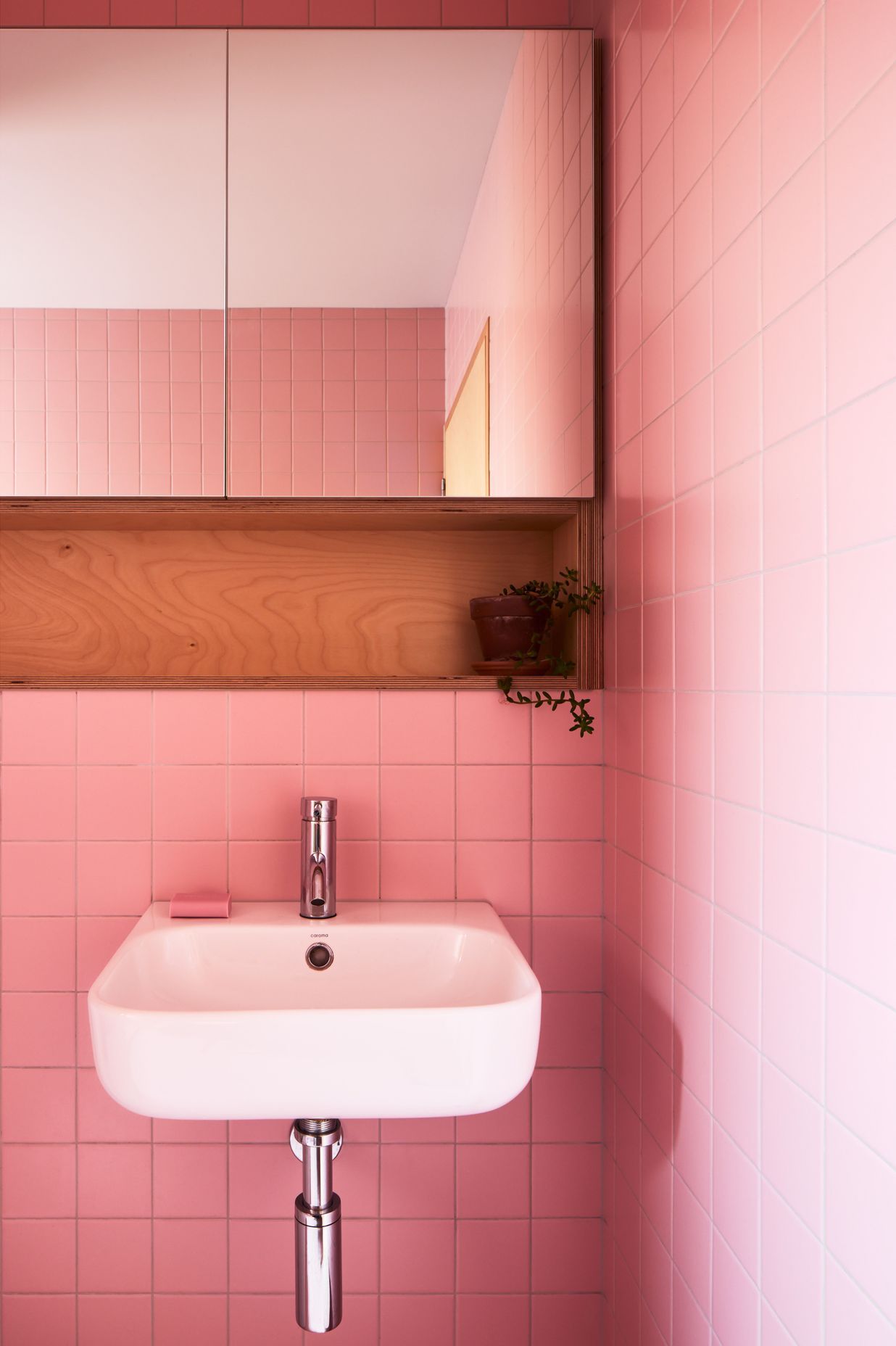 Pink bathroom tiles inject joy into everyday rituals.