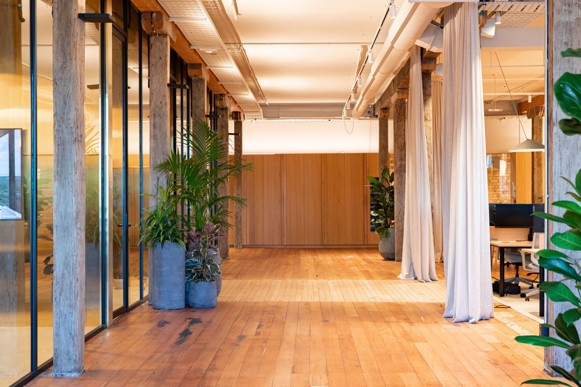 Meeting rooms are pictured to the left, with workstations across the walkway. | Photographers: Oliver Compton &amp; Millie Cossou
