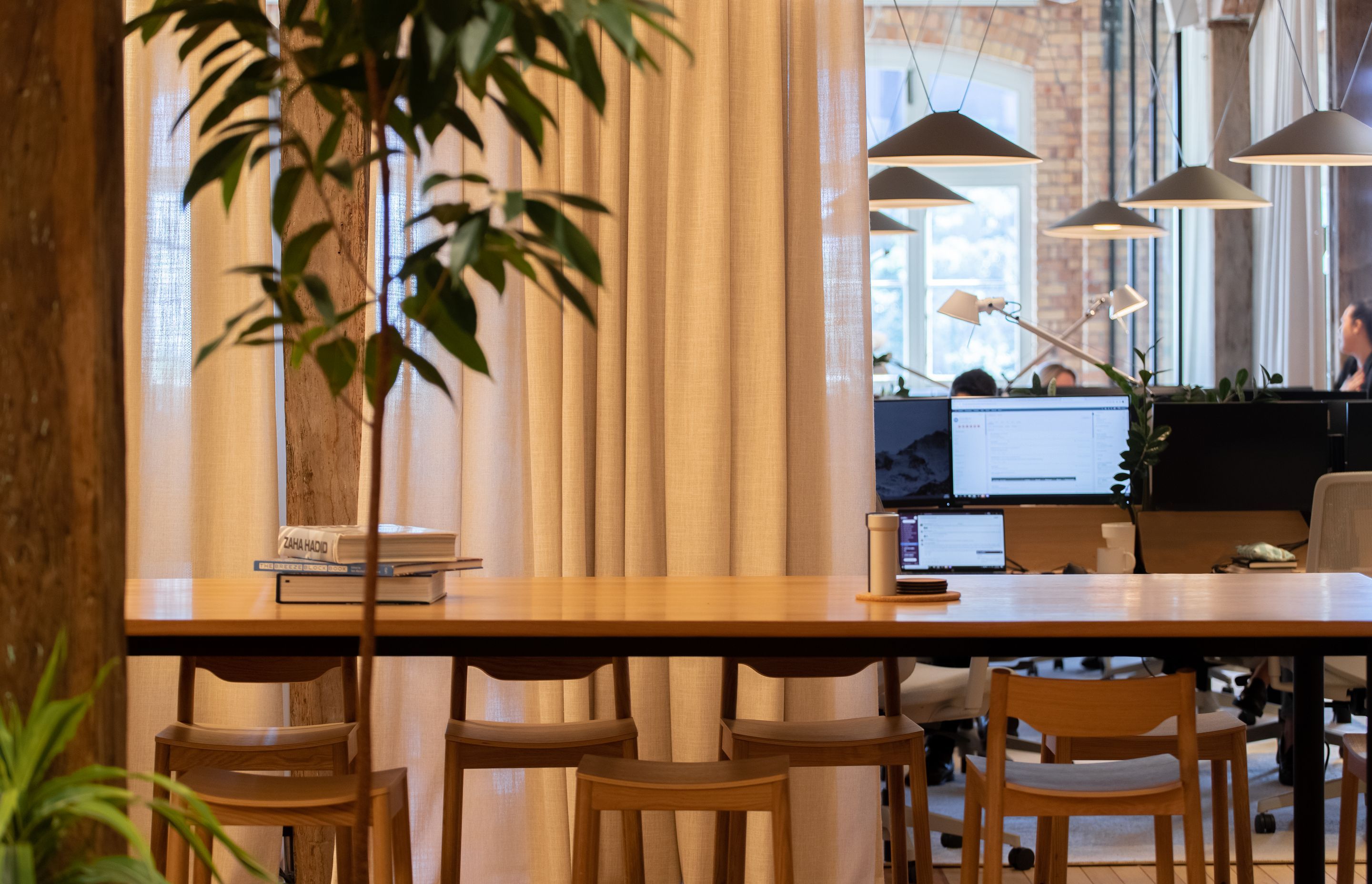 The dining table, separated from the neighbouring workstations by a full drop curtain. | Photographers: Oliver Compton &amp; Millie Cossou