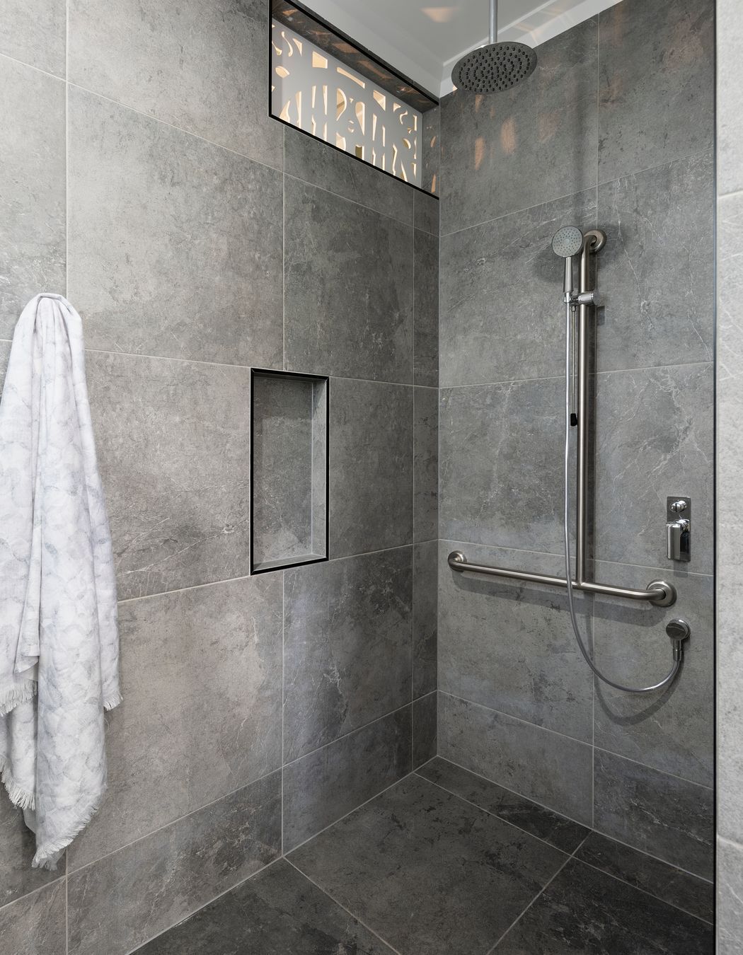 A grab bar and detatchable shower head make bathing more accessible | Auntie's Hut by 4305 Design | Photography by Angus Martin