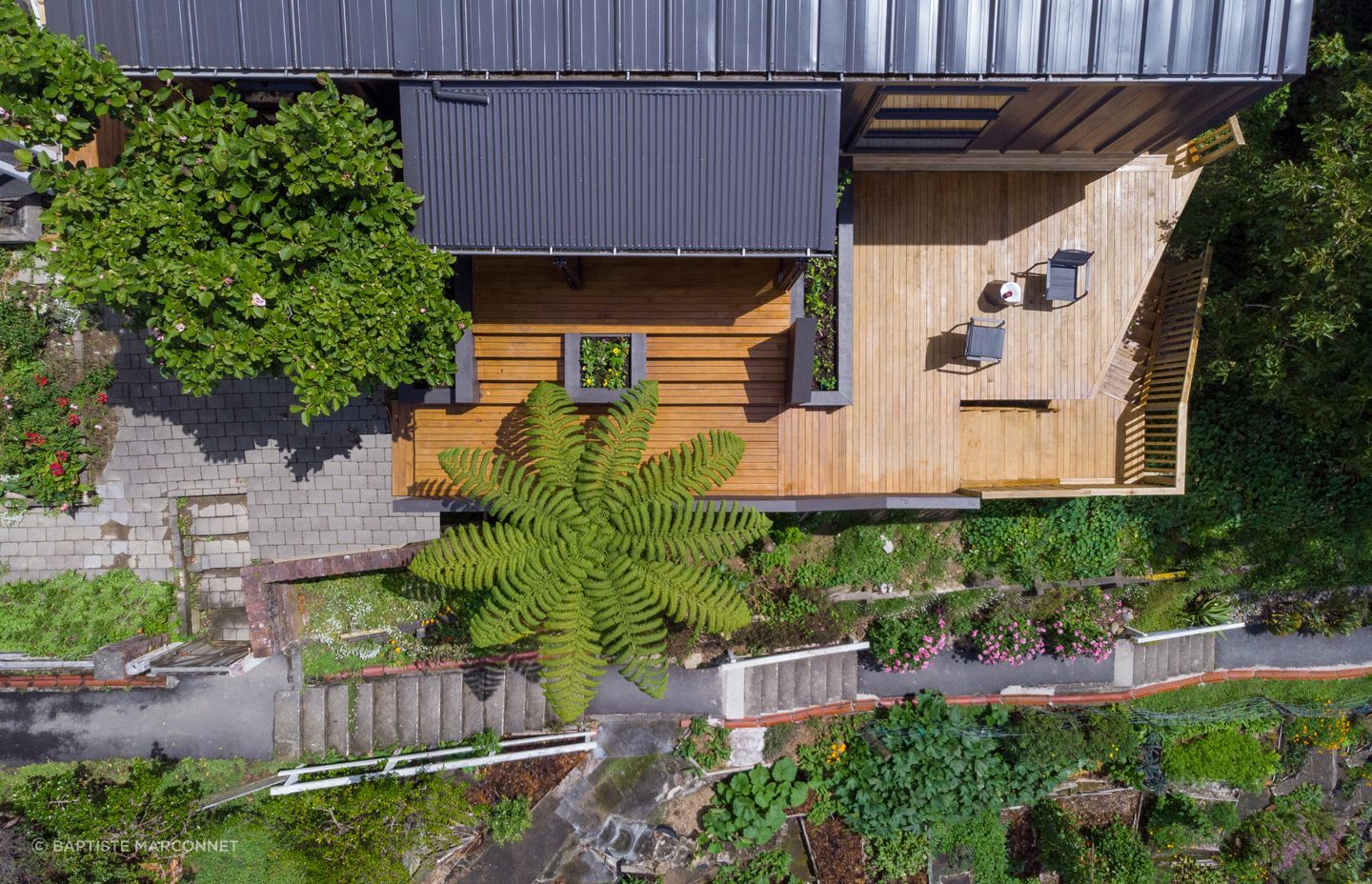 Decking has been used to extend the living space outdoors, seamlessly connecting with the sunspace module that features a set of bi-folding doors.