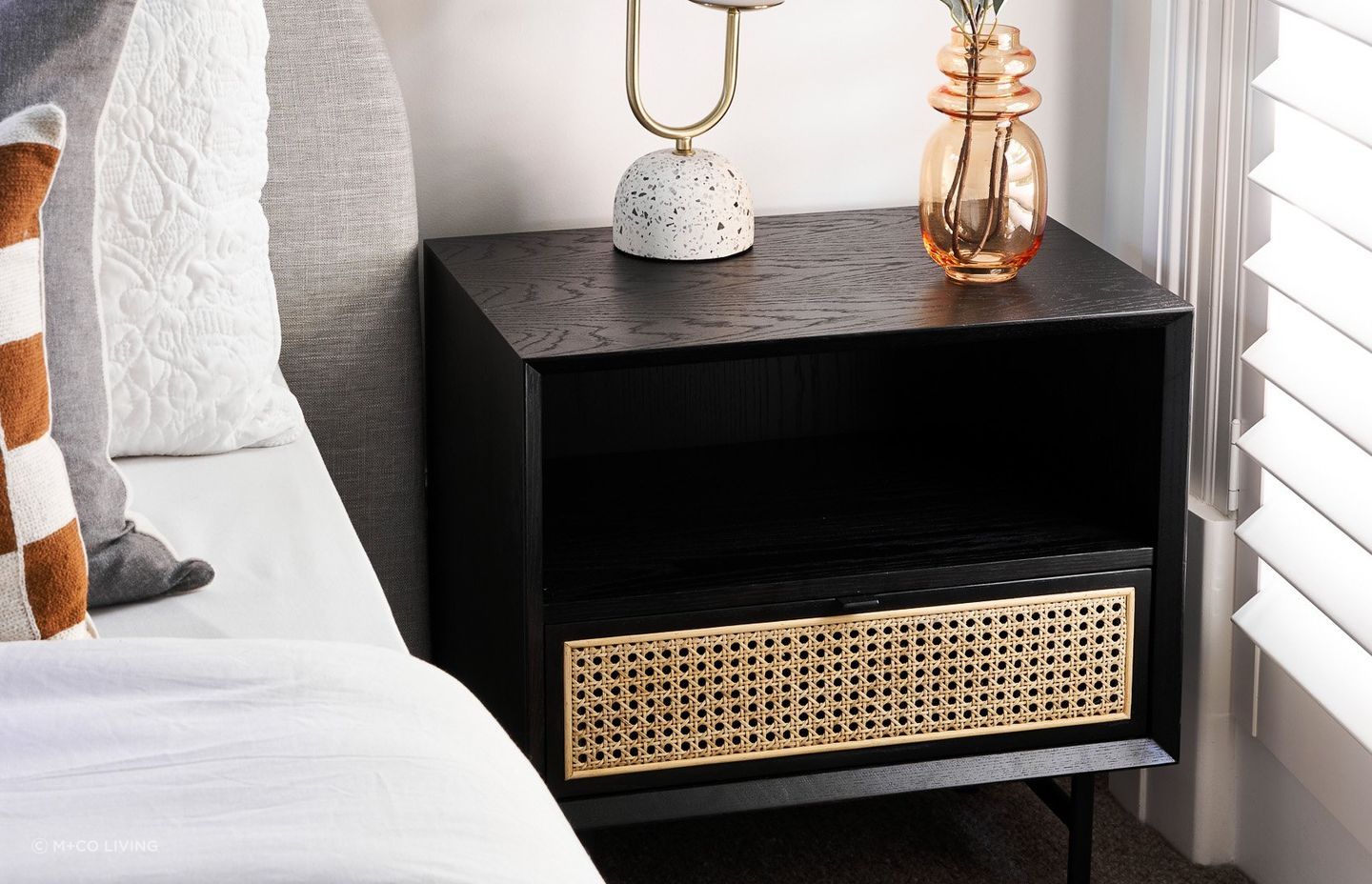 Bedside tables made of a mixture of materials, such as this one made of stained timber and rattan, incorporate different styles in their design. Featured product: Betty Side Table.
