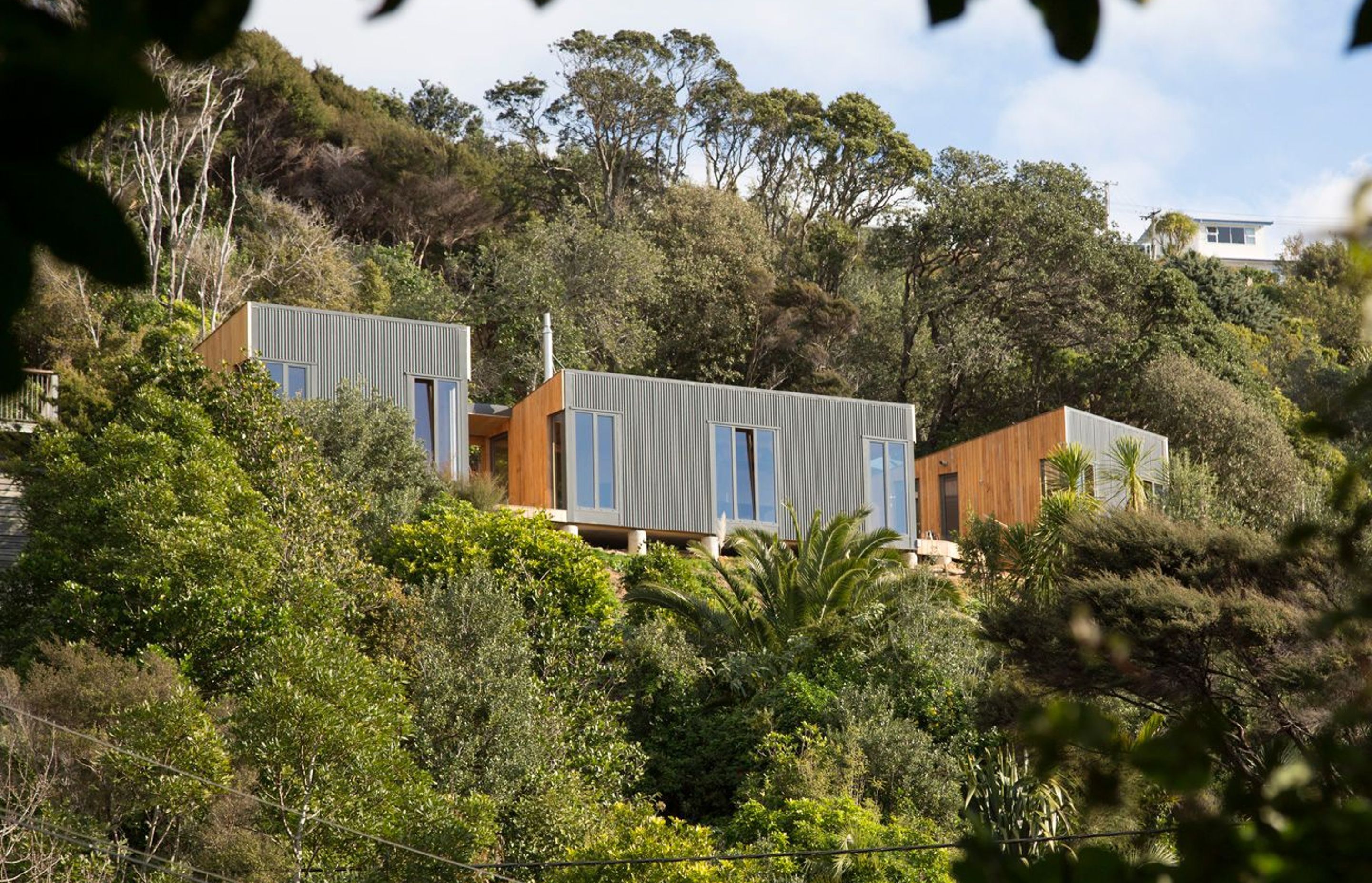 Cora House on Waiheke Island, was designed by Bonnifait + Giesen to suit a coastal environment prone to unpredictable weather with a protective facade and slim windows, connected by decks for sitting out on sunny days. Photograph by Russell Kleyn.