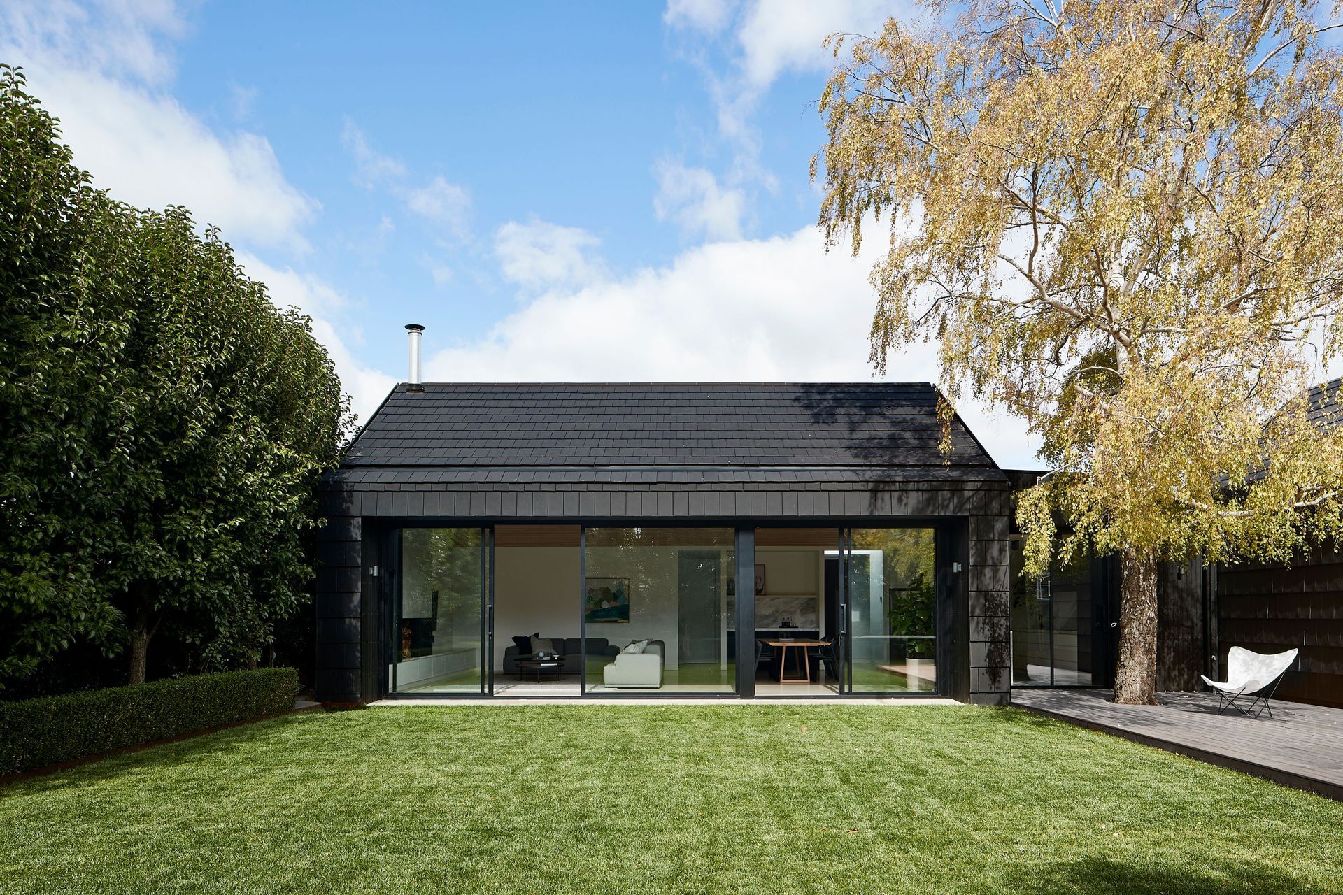The dark exterior provides a striking contrast with the outdoor greenery. Photographer: Shannon McGrath.