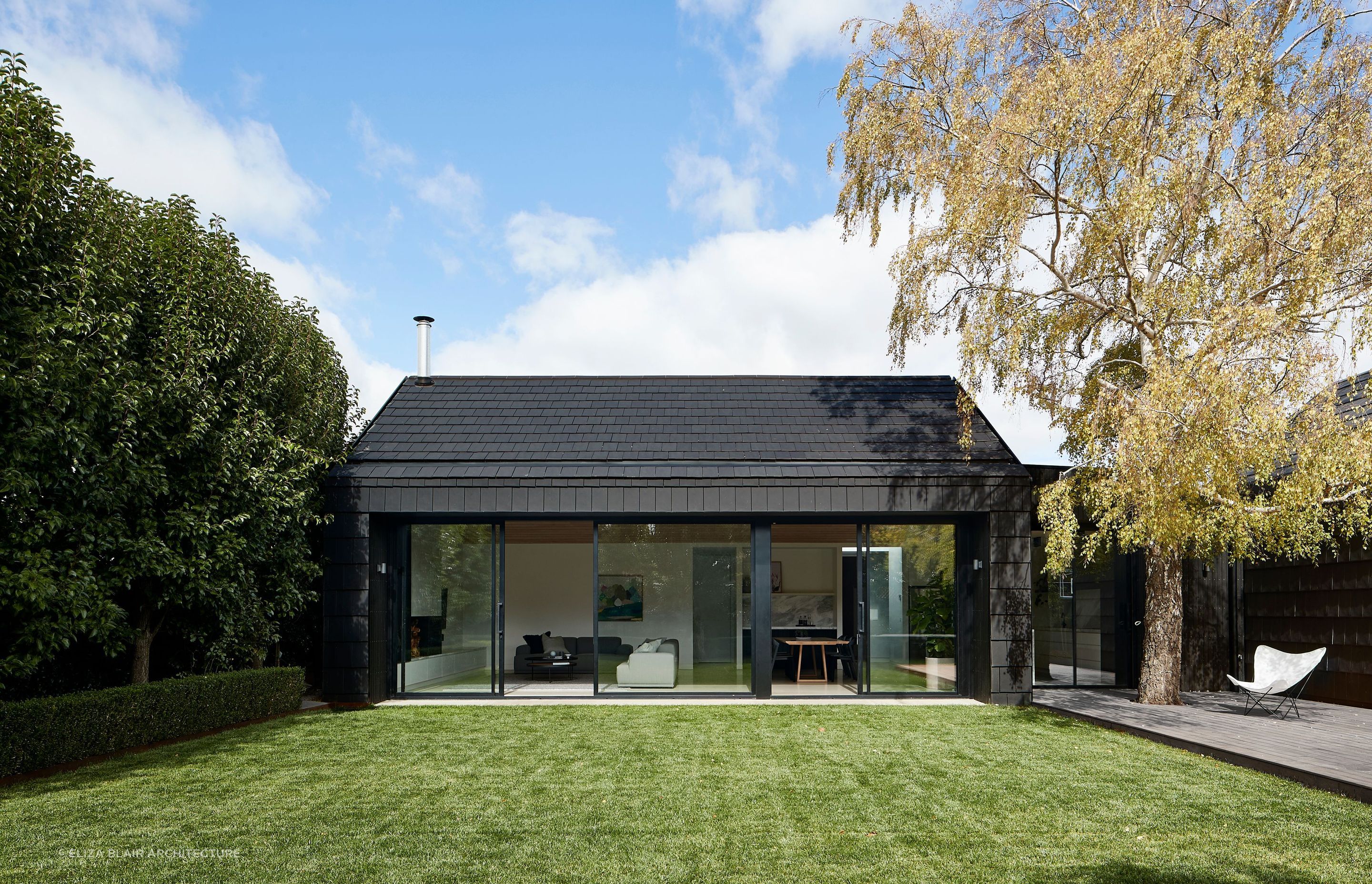 The dark exterior provides a striking contrast with the outdoor greenery. Photographer: Shannon McGrath.