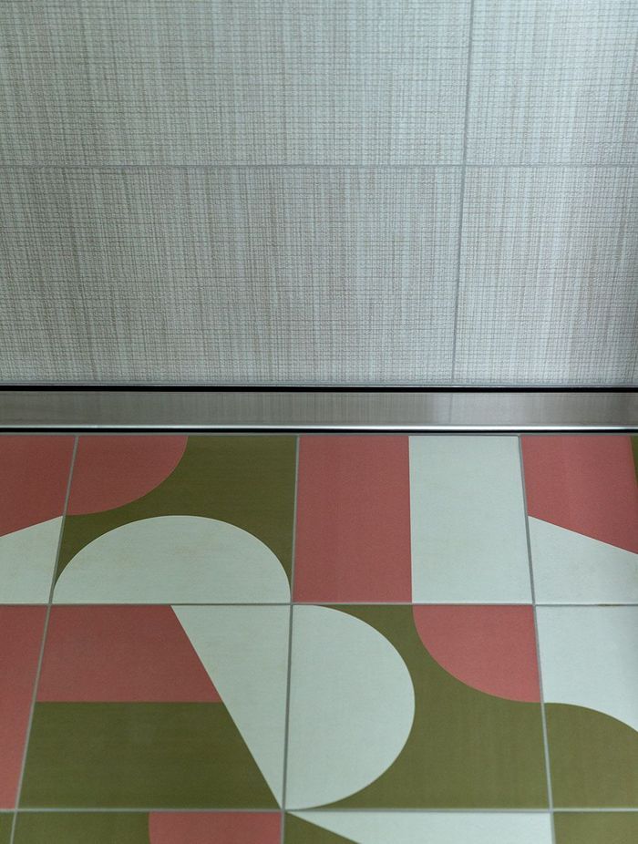 Graphic geometric tiling on the bathroom floor complements the linen-look wall tiles