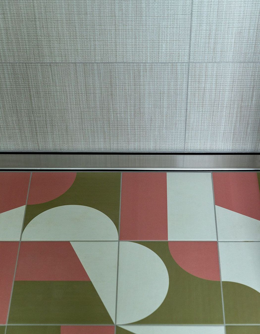 Graphic geometric tiling on the bathroom floor complements the linen-look wall tiles