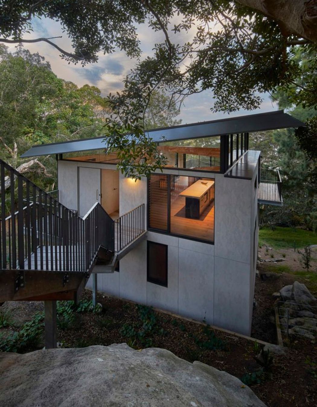 The house tucked below the rock shelf with view through the highlight windows