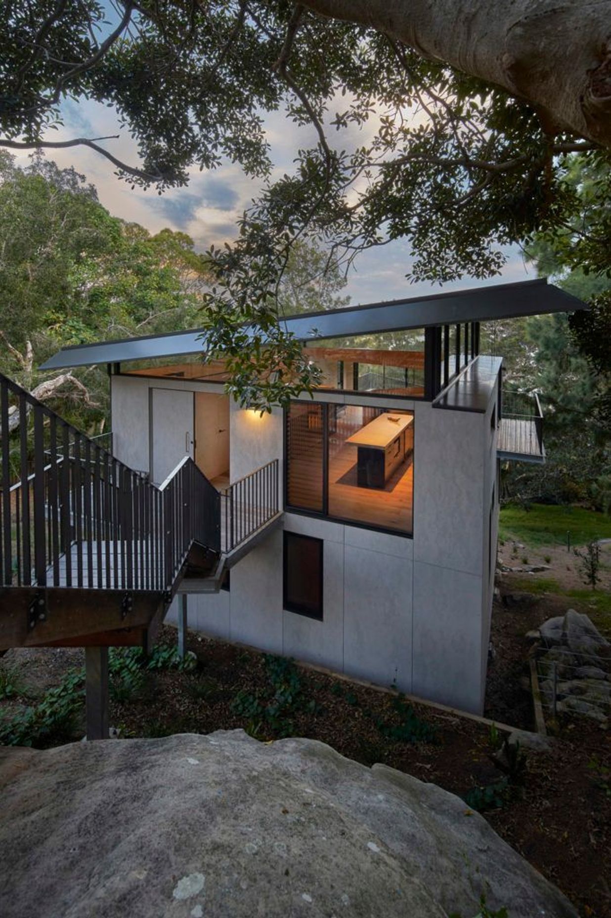The house tucked below the rock shelf with view through the highlight windows