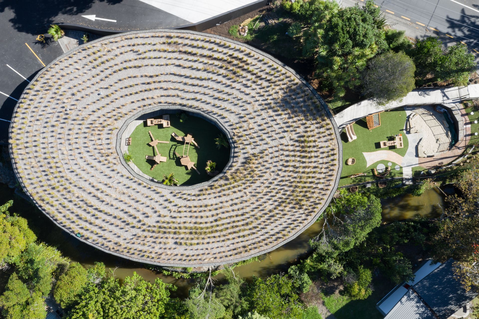 A view from above, capturing the green roof, both outdoor playgrounds, and the creek that runs alongside. | Photographer: Mark Scowen