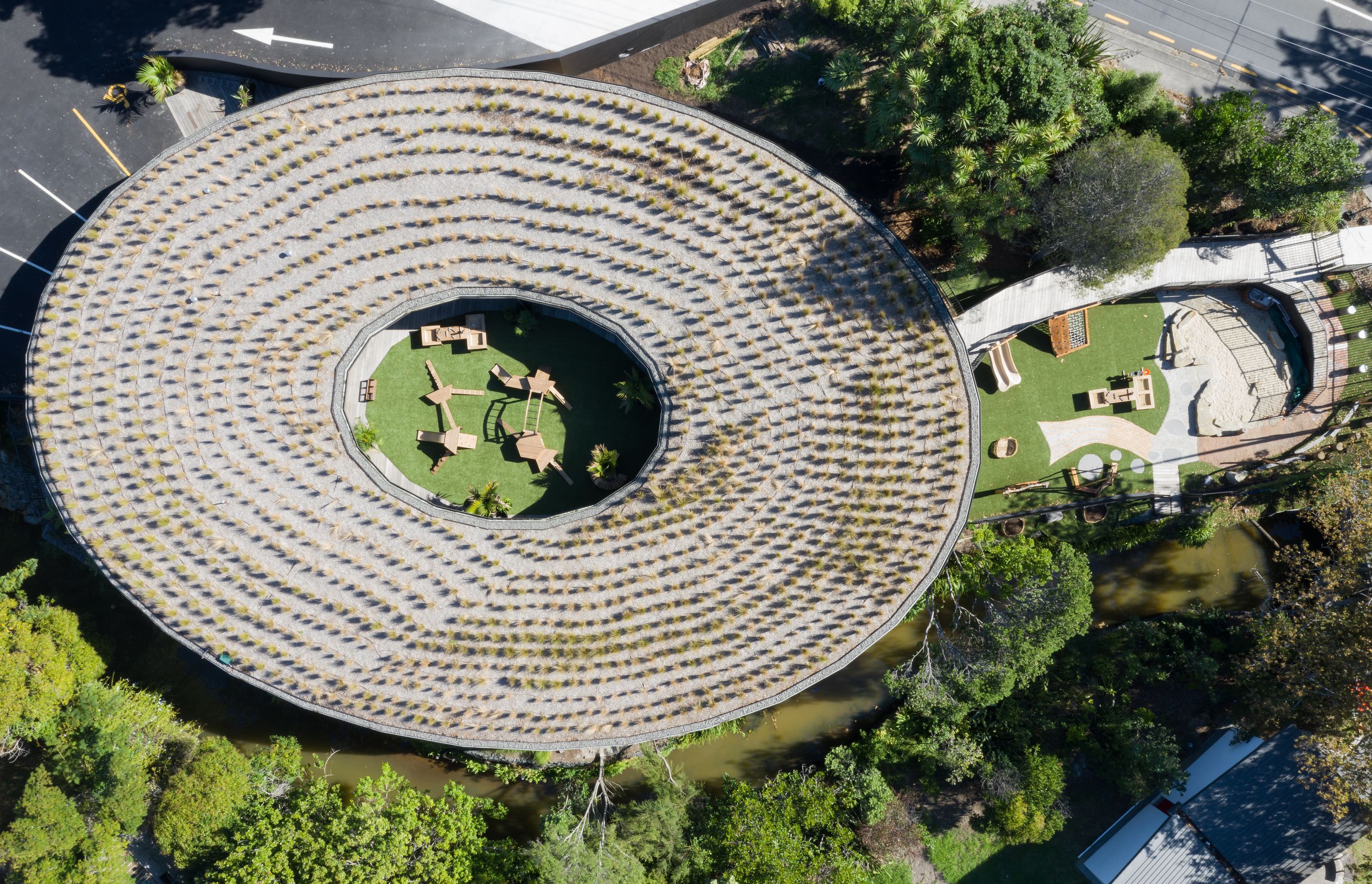 A view from above, capturing the green roof, both outdoor playgrounds, and the creek that runs alongside. | Photographer: Mark Scowen