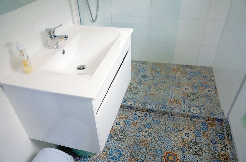 The bathroom was renovated with new fixtures, vanity, shower, and mosaic tiles. 