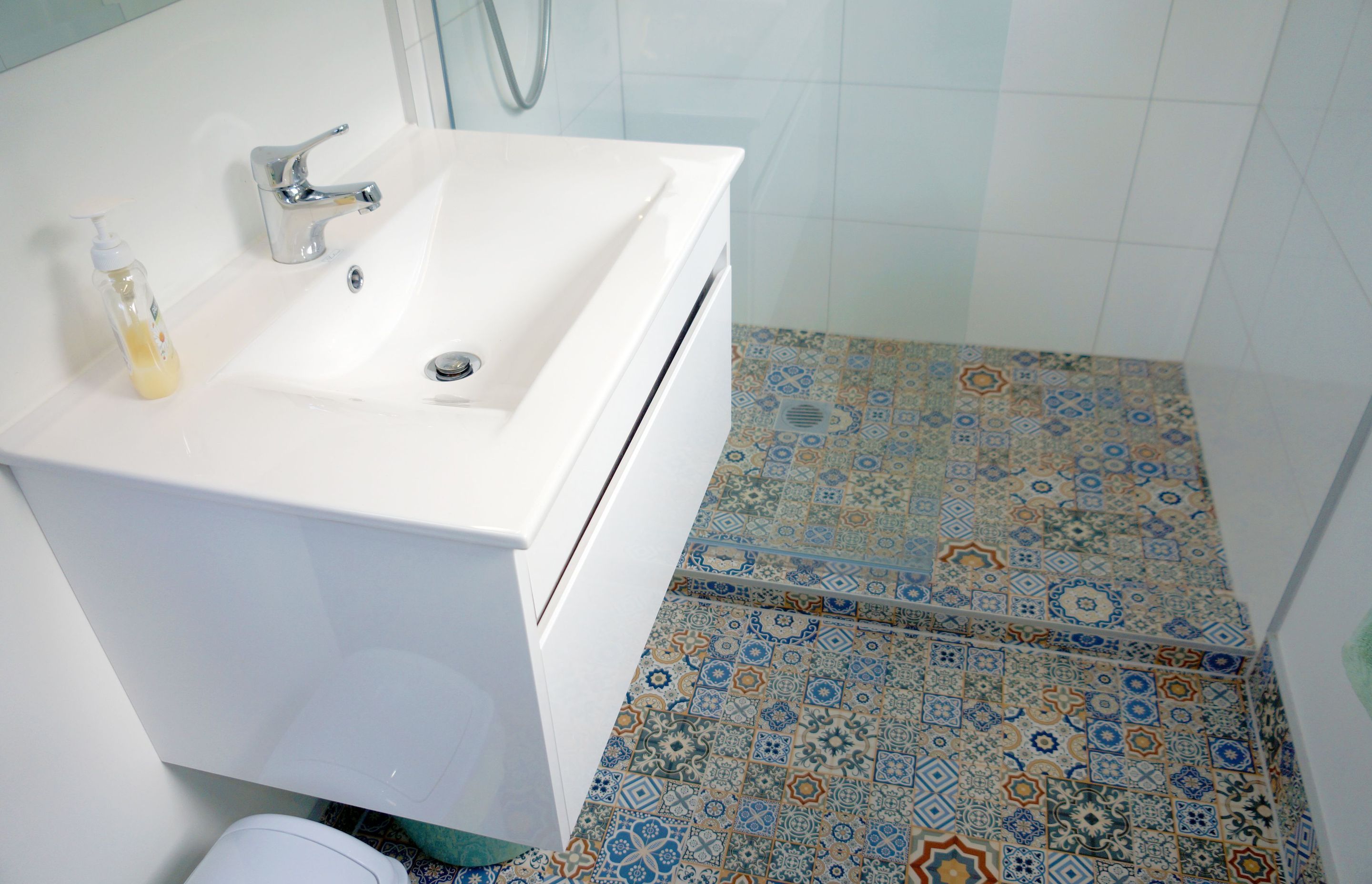 The bathroom was renovated with new fixtures, vanity, shower, and mosaic tiles. 