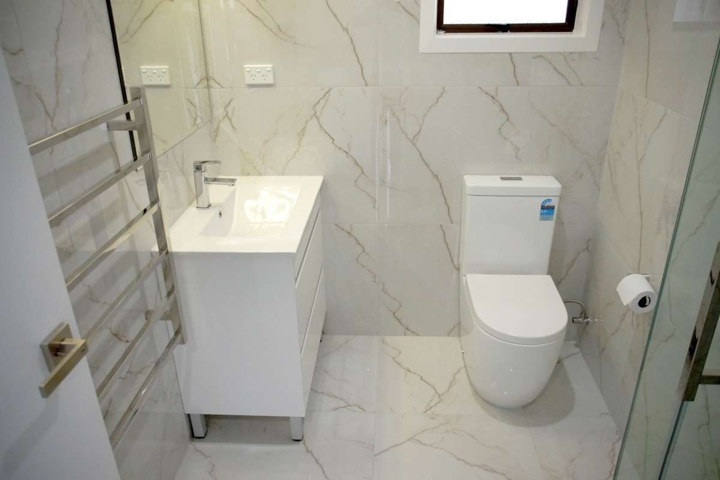 Bathroom renovation in Avondale. This ensuite features the same tiles on the floors and walls + L shaped corner shower, bathtub, vanity and toilet.