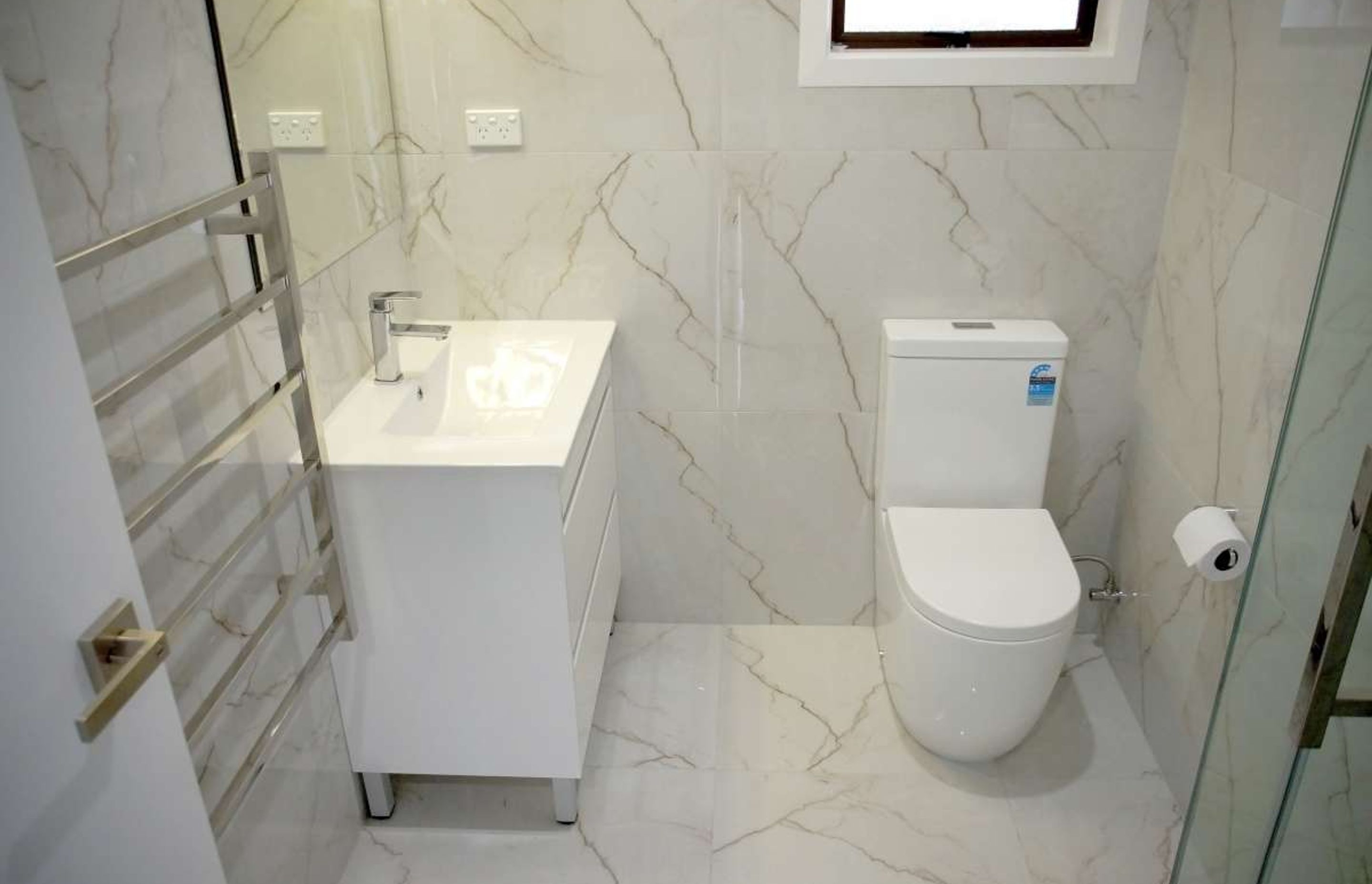Bathroom renovation in Avondale. This ensuite features the same tiles on the floors and walls + L shaped corner shower, bathtub, vanity and toilet.