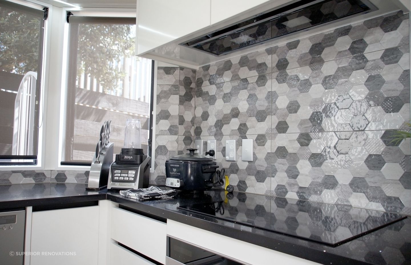Kitchen renovation in Bucklands Beach: Hexagon shaped black and grey textured tiles were added as a backplash to add interest, drama and texture to the kitchen.