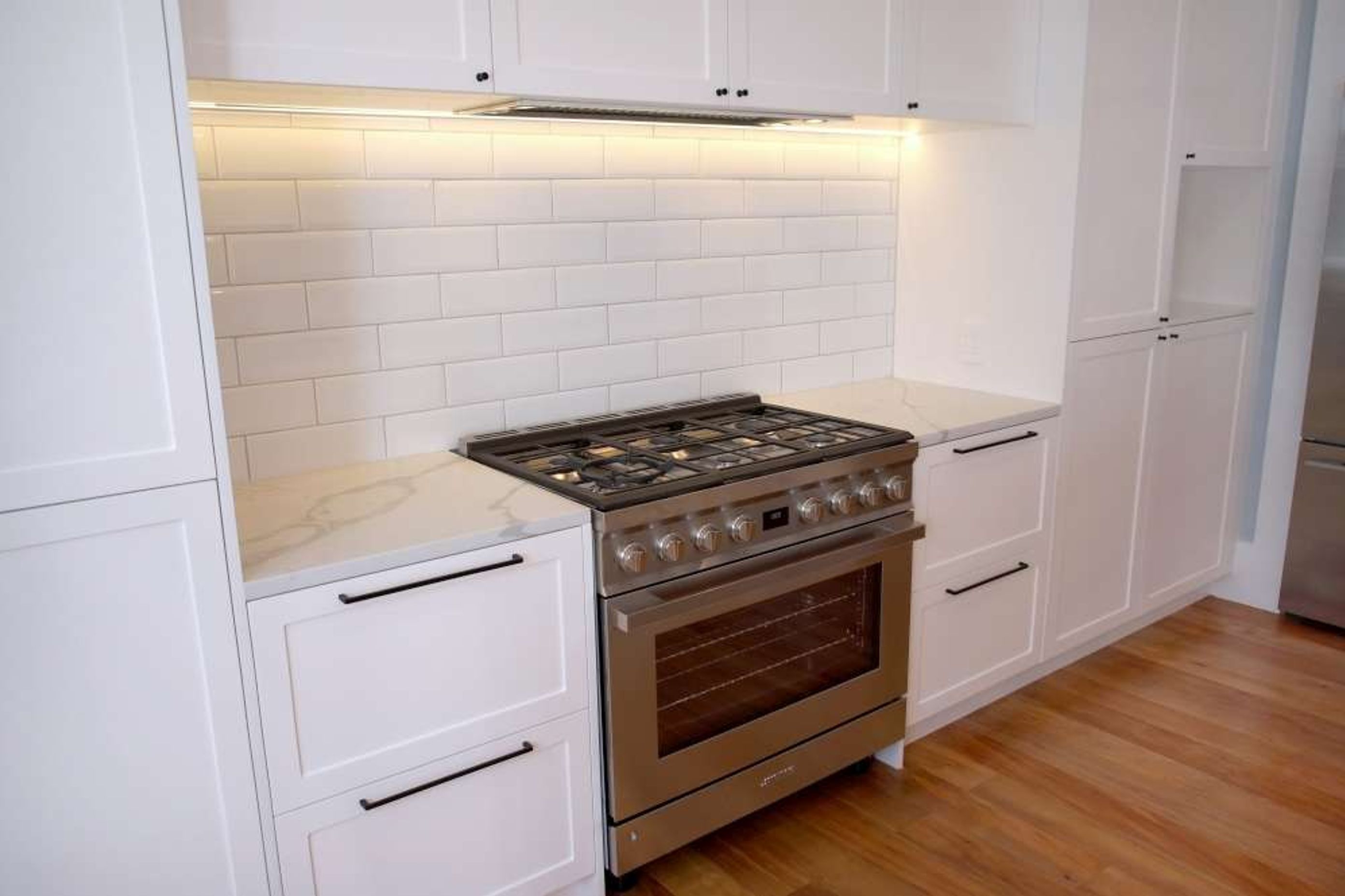 A grey cooking range was used with white subway tiles as a backsplash for a timeless classic design – Kitchen renovation in Epsom