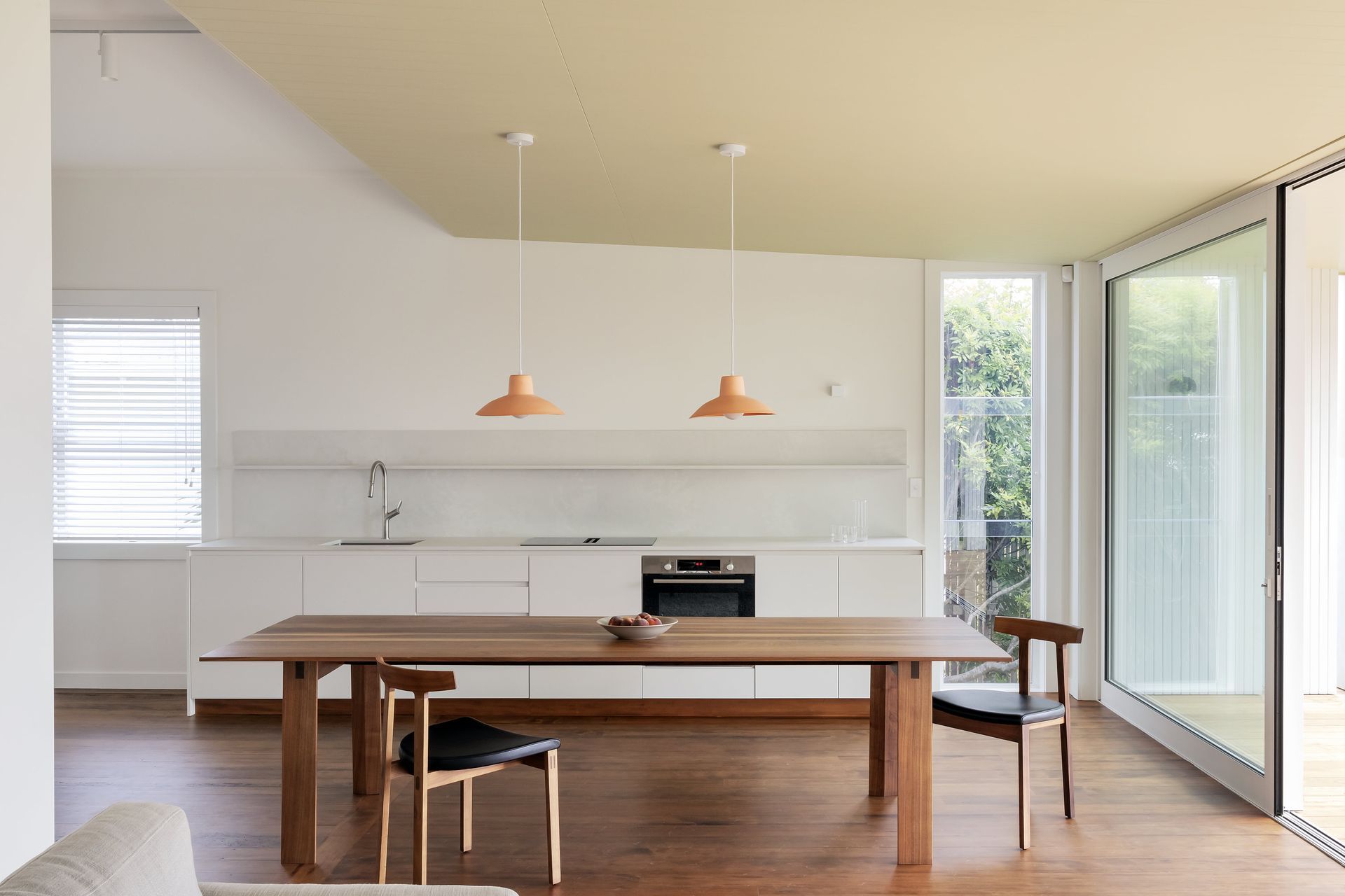 Natural light floods the minimalist kitchen and dining area through floor-to-ceiling glass sliding doors. Photo: David Straight