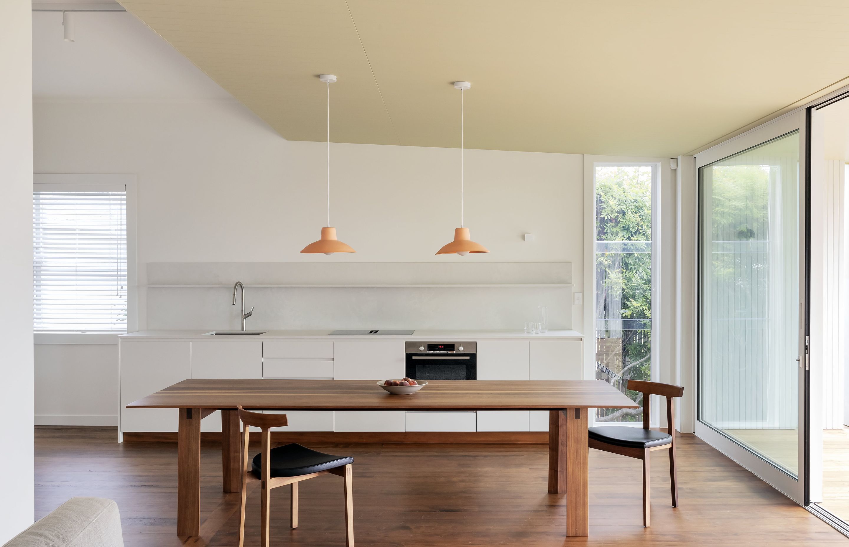 Natural light floods the minimalist kitchen and dining area through floor-to-ceiling glass sliding doors. Photo: David Straight