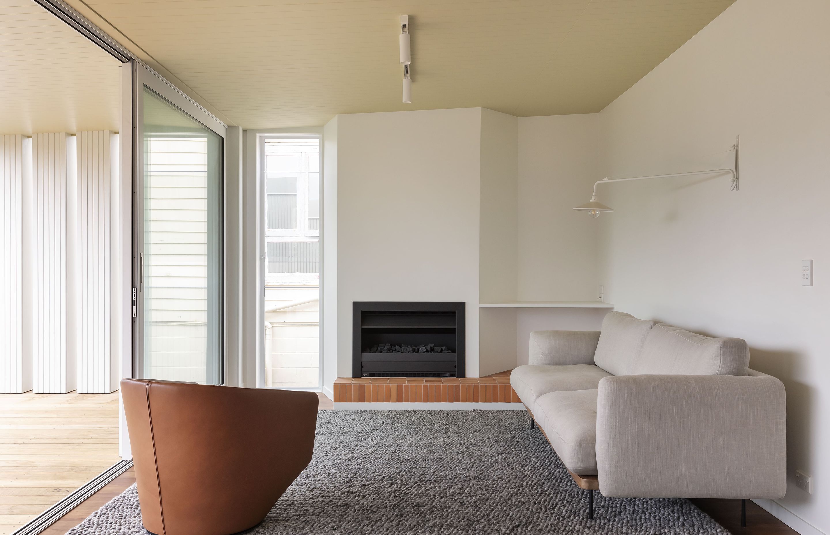 A geometric wall and brick hearth add visual interest to the lounge. Photo: David Straight