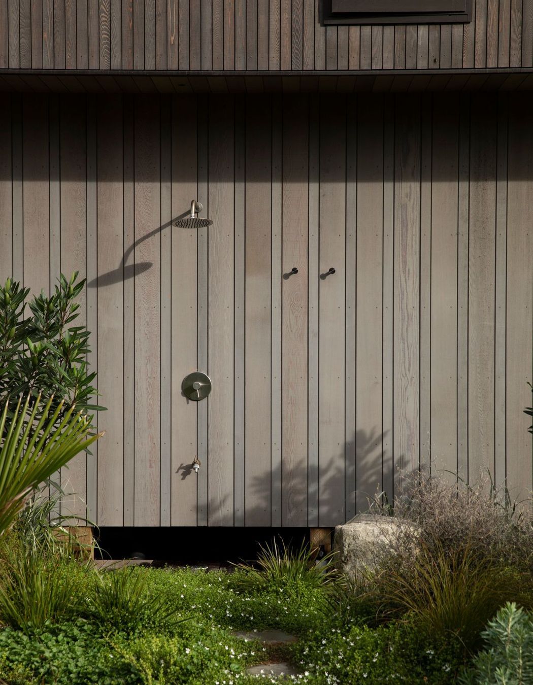 On the south side of the vertical building form, an outdoor shower is tucked away. Image credit: David Straight