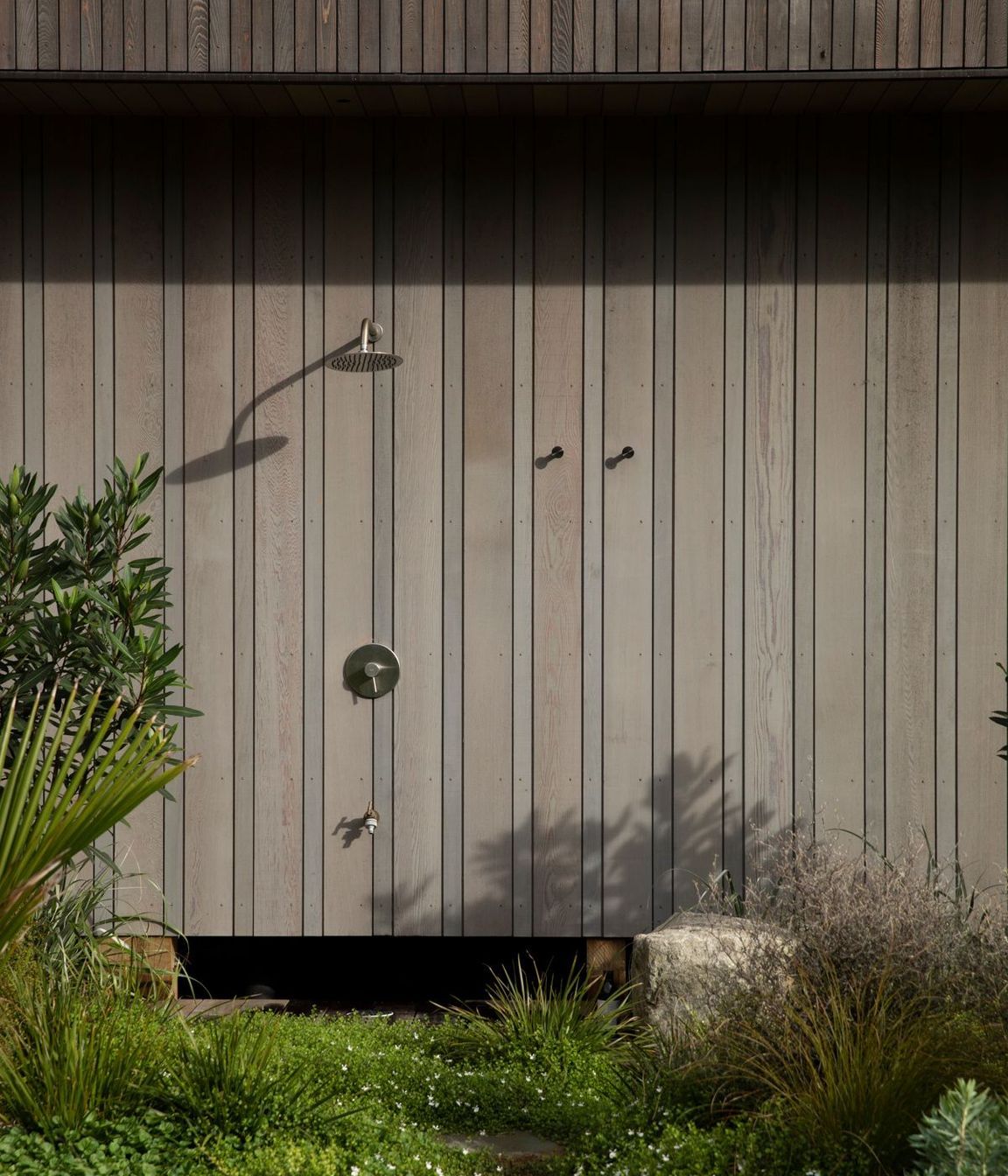 On the south side of the vertical building form, an outdoor shower is tucked away. Image credit: David Straight