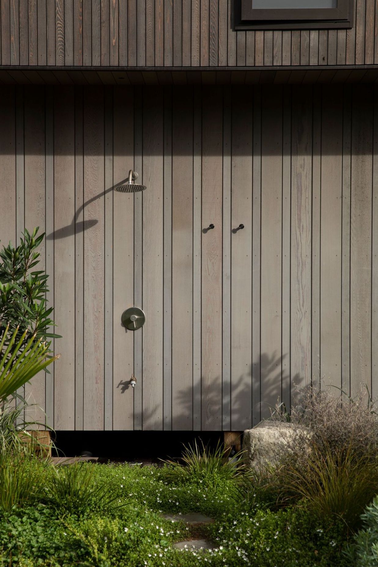 On the south side of the vertical building form, an outdoor shower is tucked away. Image credit: David Straight