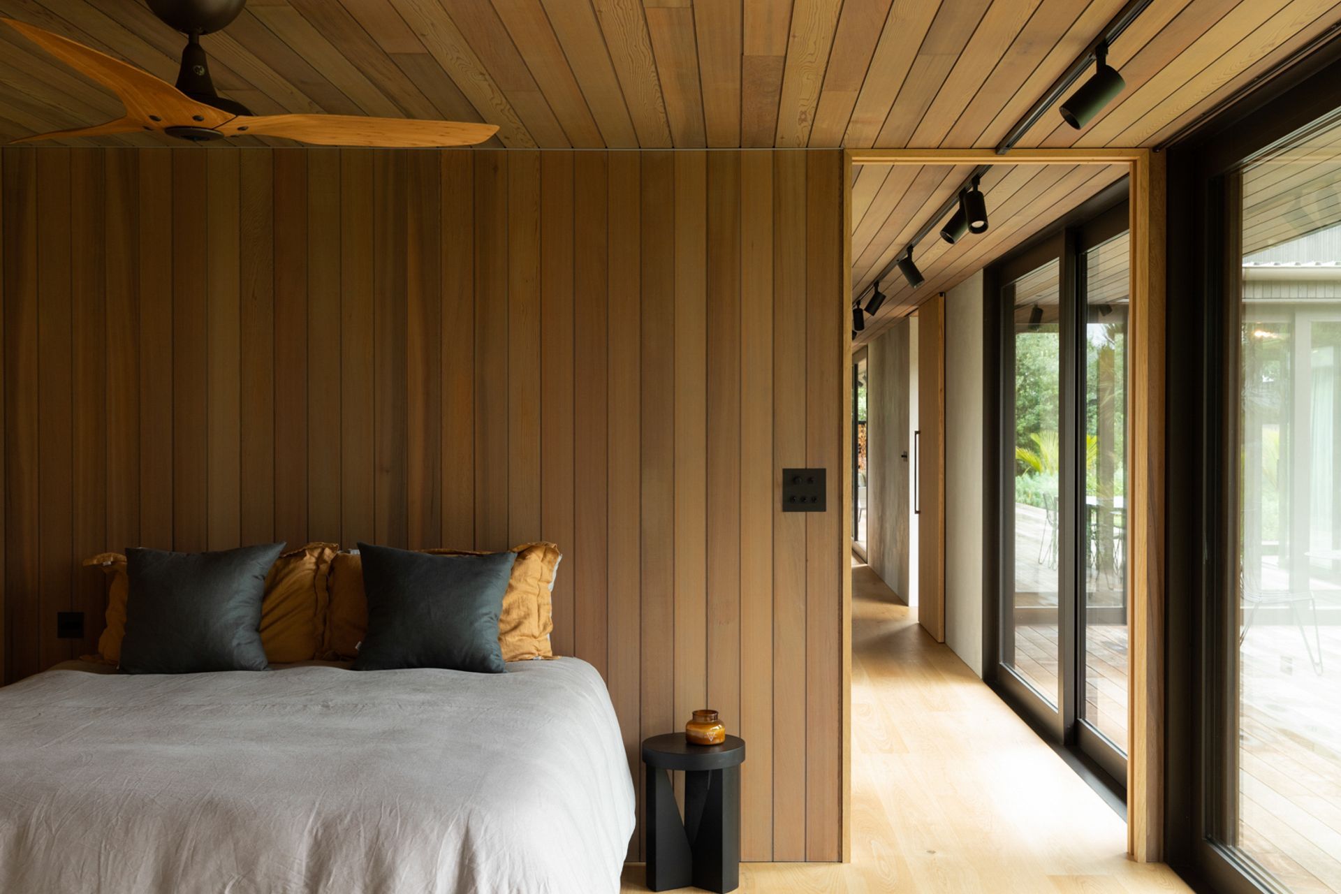 Each of the downstairs bedrooms uses timber linings to ground the space and reflect the natural environment. Image credit: David Straight