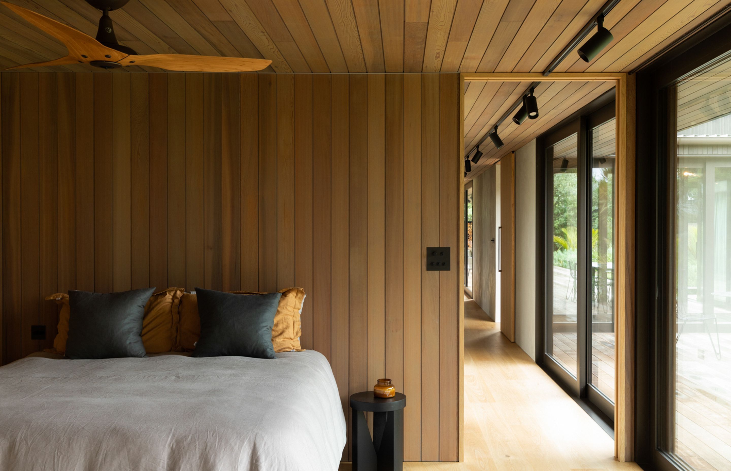 Each of the downstairs bedrooms uses timber linings to ground the space and reflect the natural environment. Image credit: David Straight