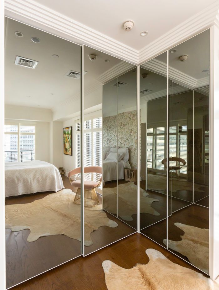 This interior by Stratford Interior Design showcases smokey glass mirrored doors, which contrast nicely against the white frames and traditional mouldings in this apartment: "This was in a very small apartment and having that dark mirror on the wardrobes really created the illusion of space," says Gina.