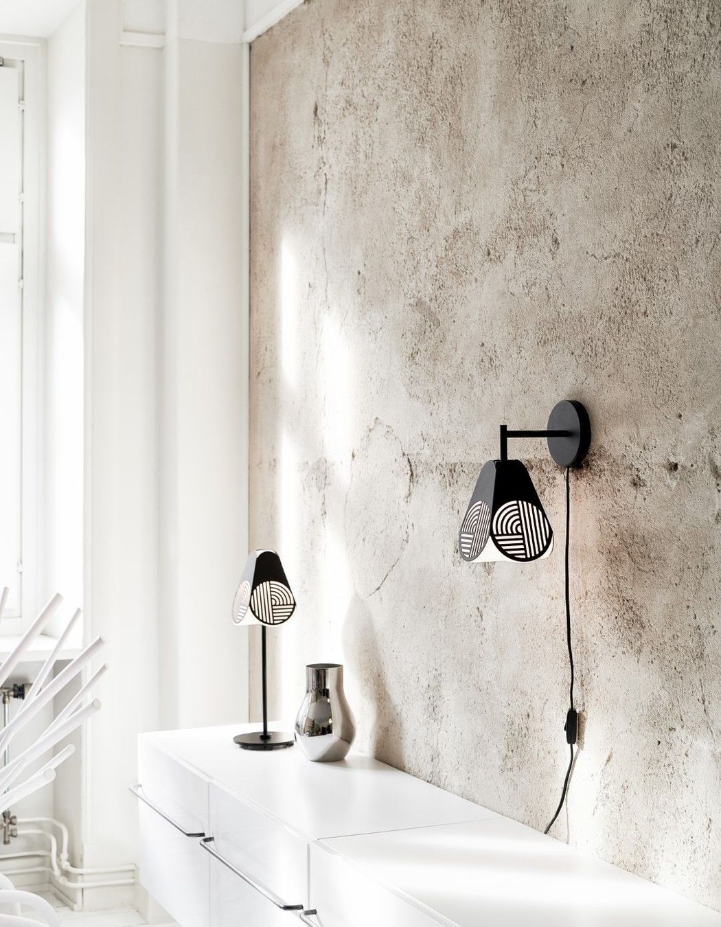 The Oblure Notic Collection lighting pieces add graphic, textural design elements to a space with simple black forms and opaline diffusers. Add definition to a soft, serene space with some simple, strong details like this pair of table and wall lamps.