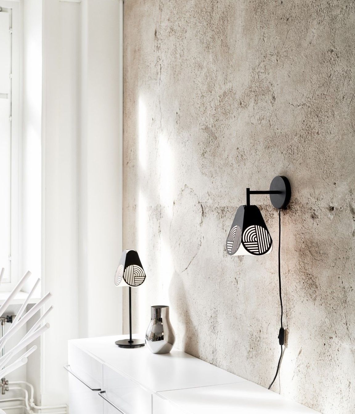 The Oblure Notic Collection lighting pieces add graphic, textural design elements to a space with simple black forms and opaline diffusers. Add definition to a soft, serene space with some simple, strong details like this pair of table and wall lamps.