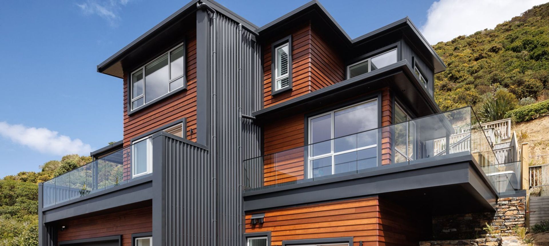 Cedar wood weatherboards juxtapose with black metal cladding, bringing an architectural flair to Tom Wilson's Ōwhiro Bay home