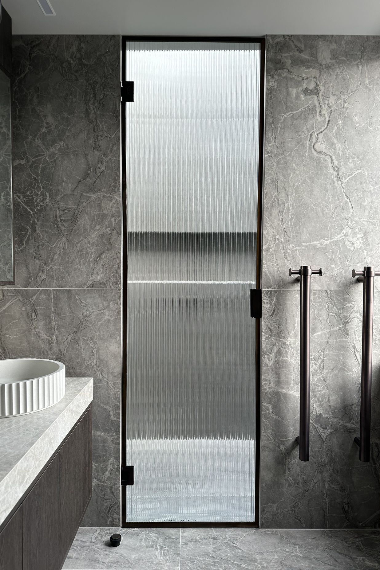 The reeded glass shower door is a beautiful, modern touch in this bathroom.