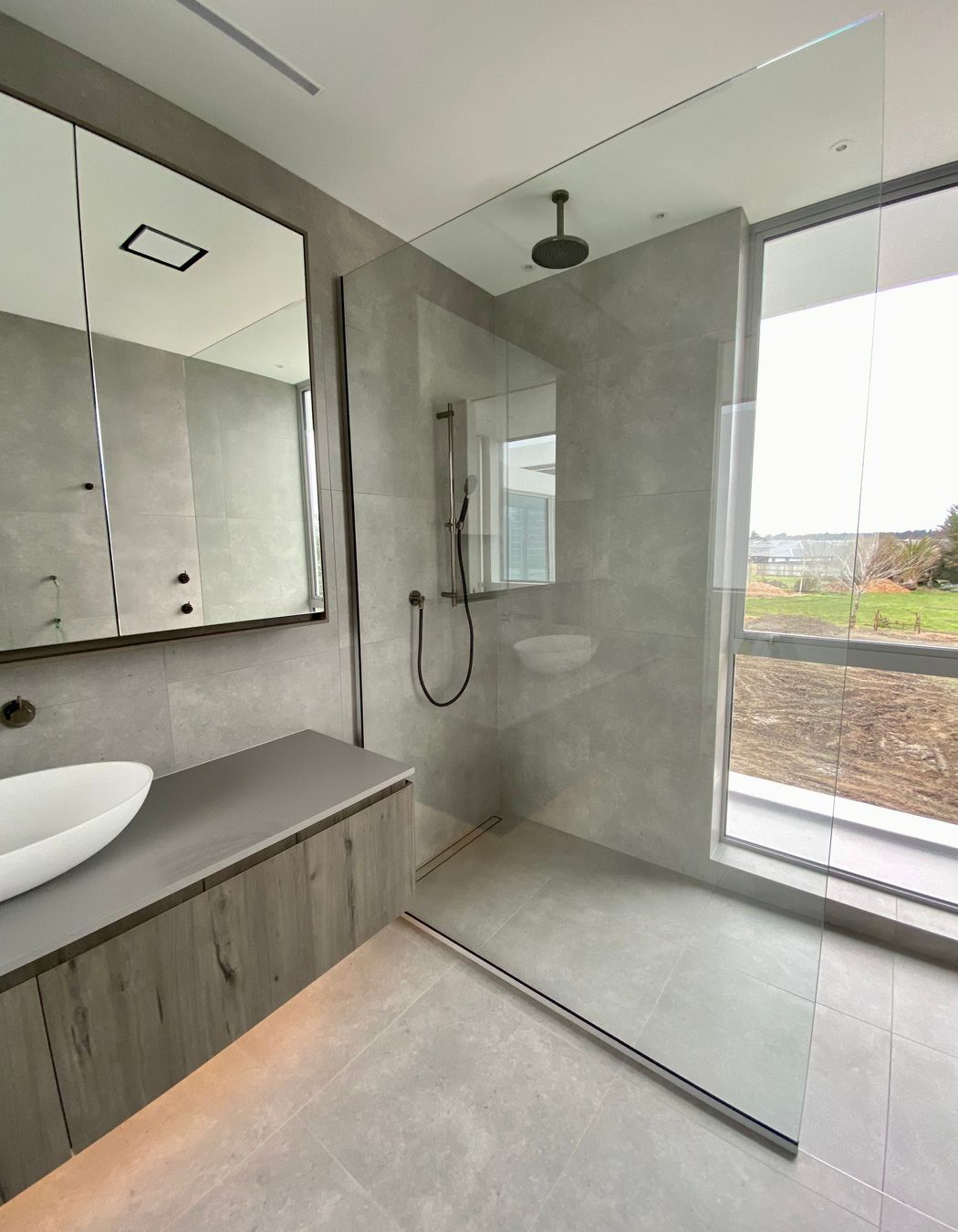 Rather than close the shower off, the designer has opted for a fixed panel shower screen that allows the light to flow freely.