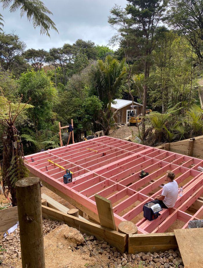 Pole foundations are started, with the young family watching on from the tiny home at the bottom of the section.