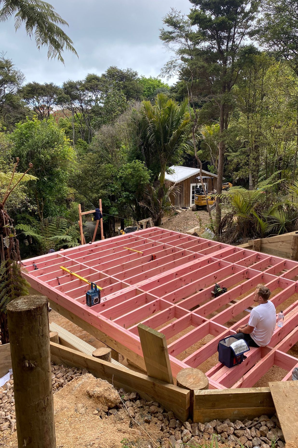 Pole foundations are started, with the young family watching on from the tiny home at the bottom of the section.