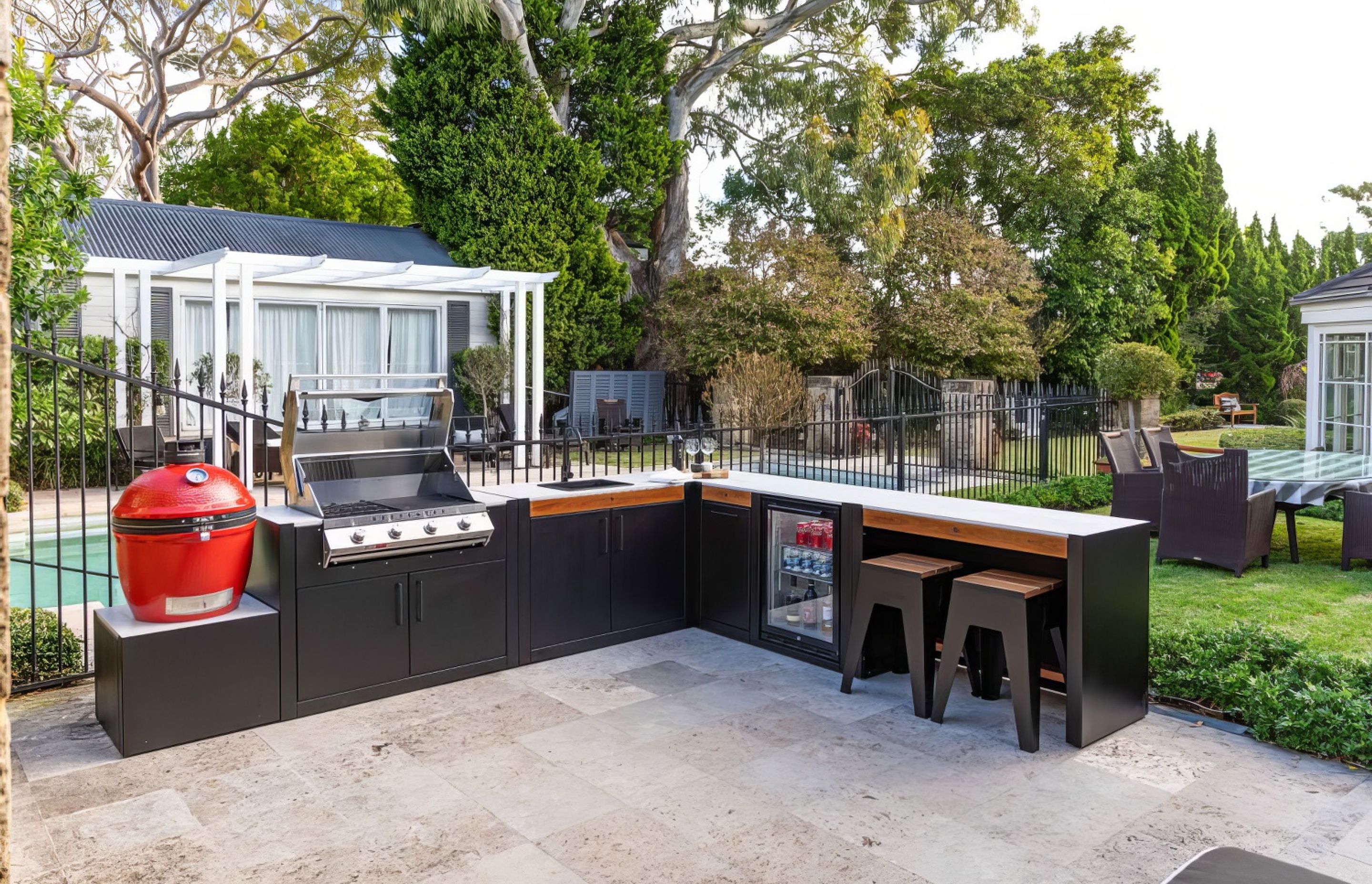 Backyard kitchen with a Kamado smoker, BBQ, sink and bar