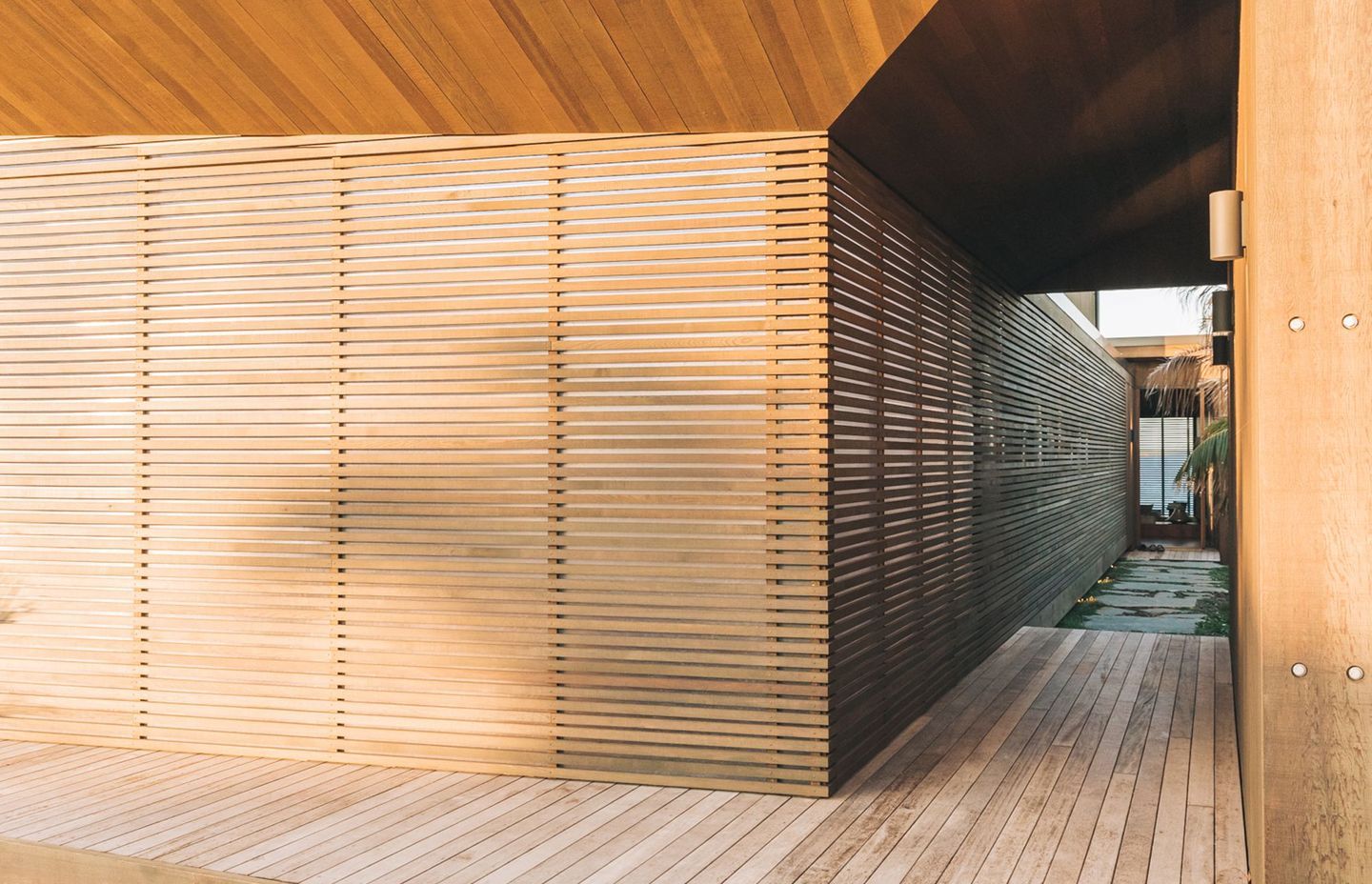 Entrance to the home is by way of a journey along a walkway that moves from decking to pavers to arrive at the front door.