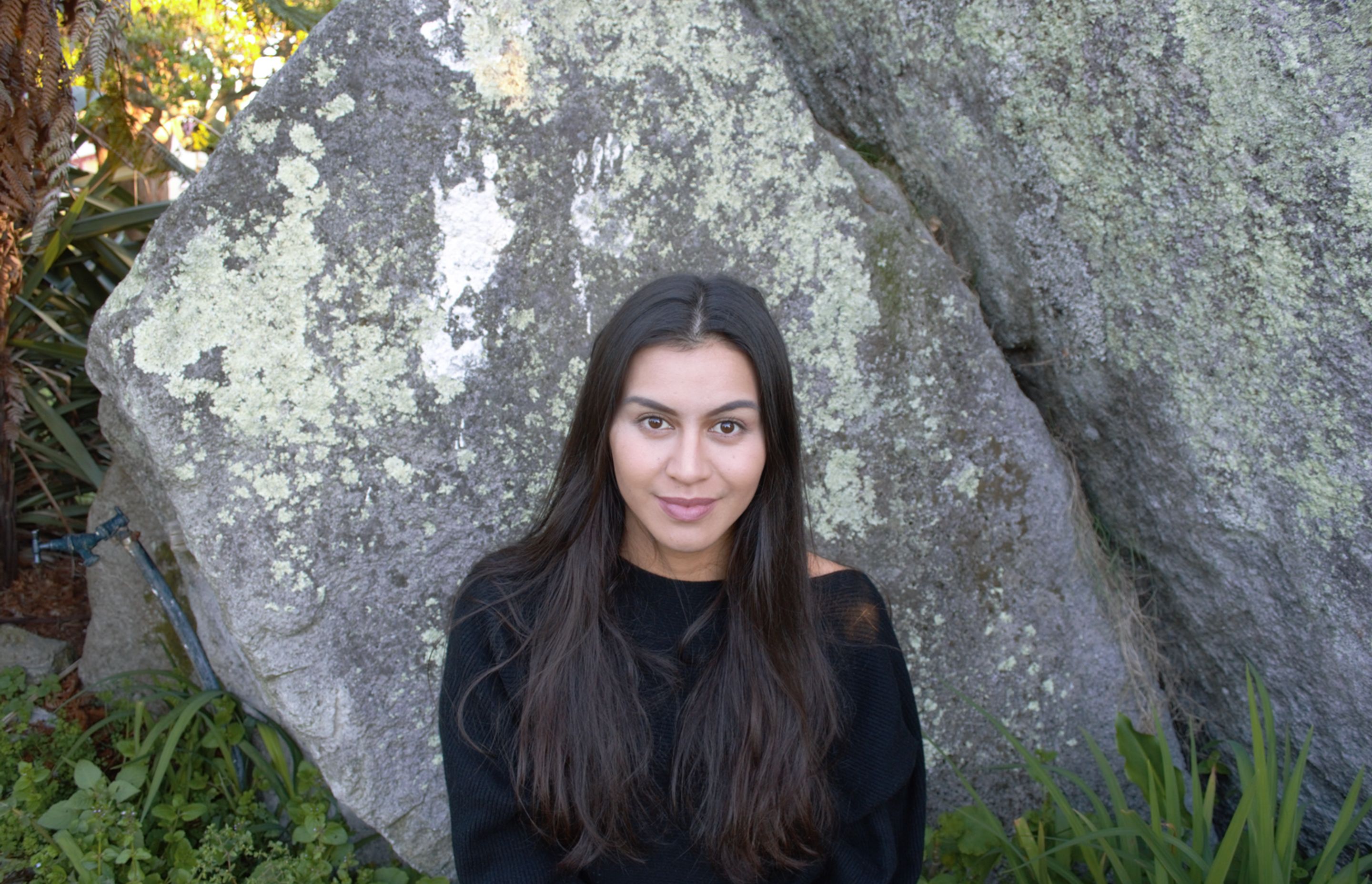 Danielle sitting in front of Hinemoa’s rock at her tūrangawaewae, Ōwhata Marae –where she based her thesis research.