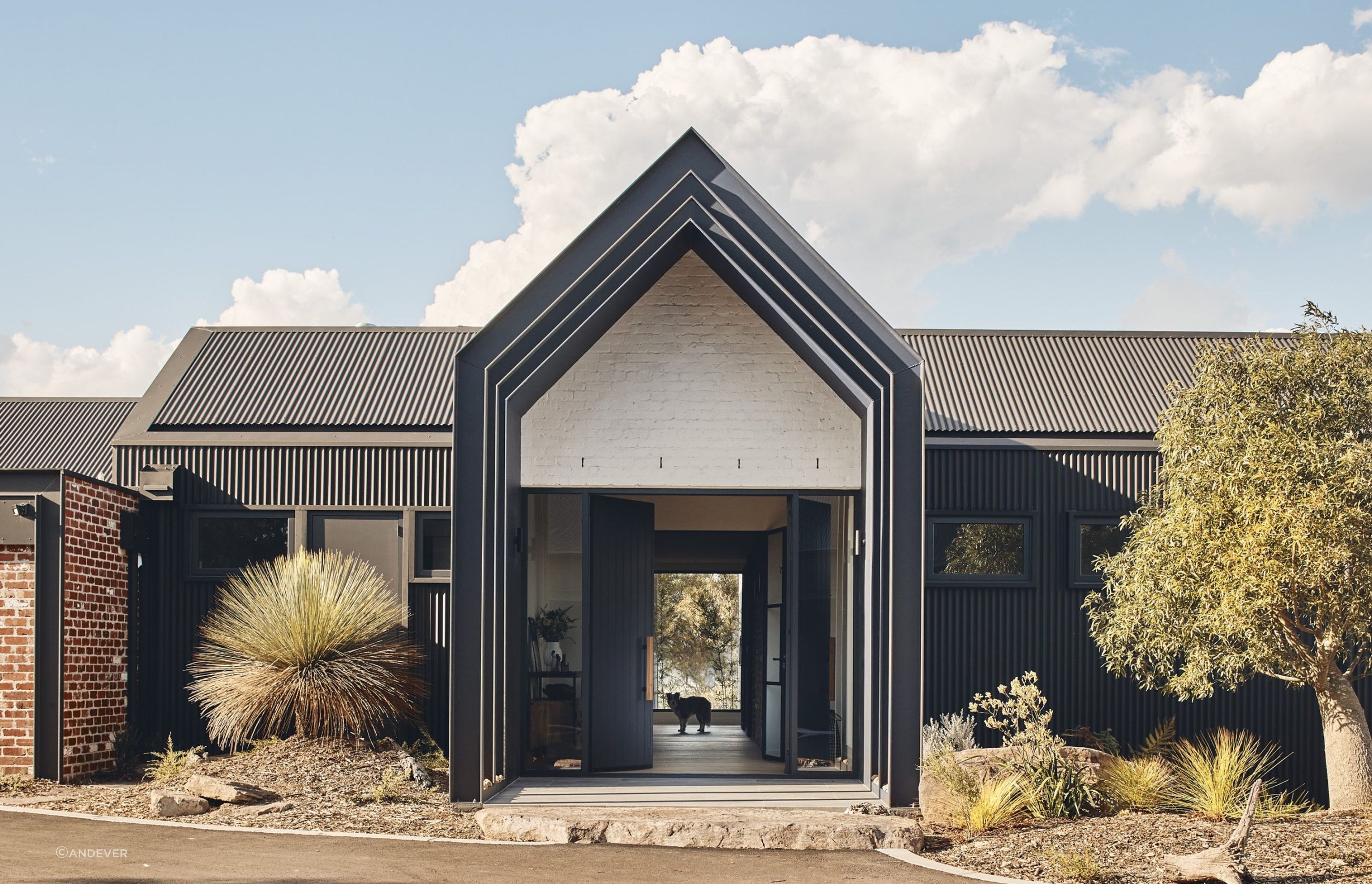 The home's exterior mixes simple gable roofs with recycled brick and corrugated cladding. Photography: Peter Bennetts