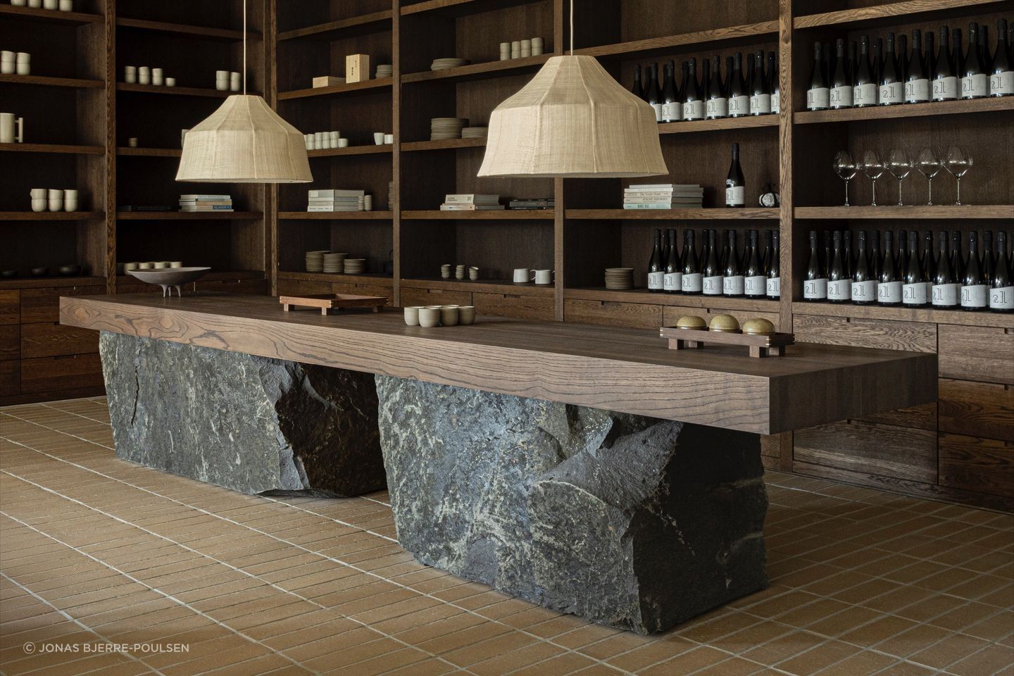 The reception sets the tone with dark timber cabinetry, stone and handcrafted objects. Photography by Jonas Bjerre-Poulsen.